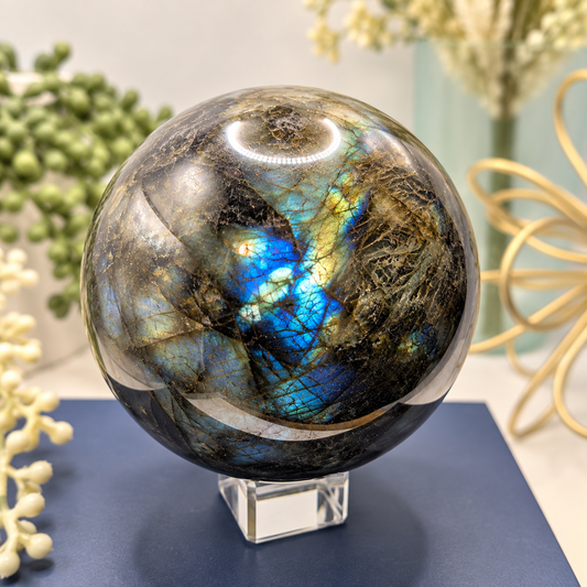Large 102mm Labradorite sphere with vivid blue and gold flash displayed in a boutique setting